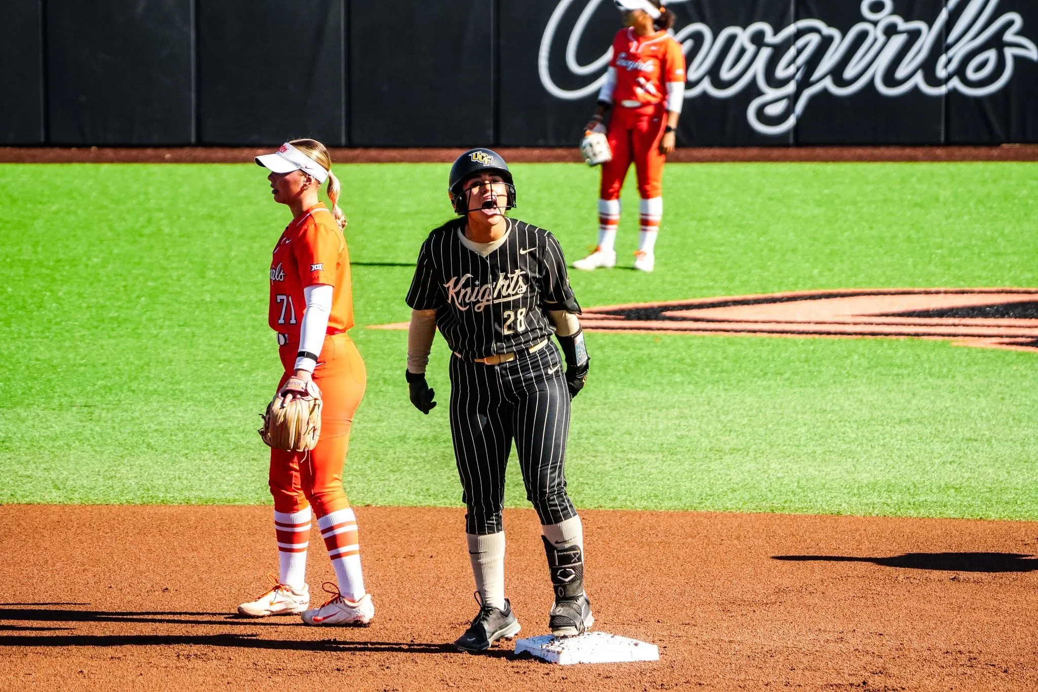 Izzy Mertes shouting in celebration while standing on second base in UCF's black pinstripe uniform