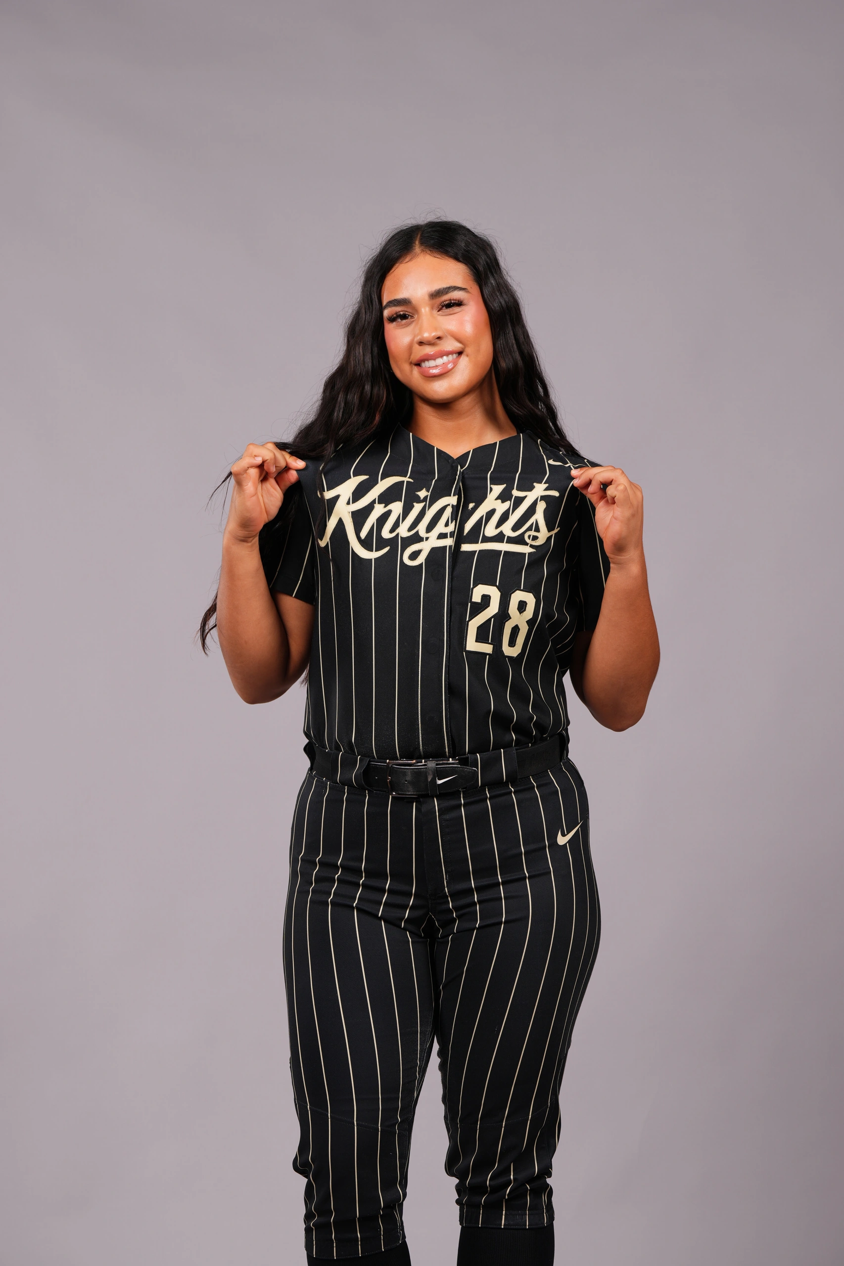Studio portrait of Izzy Mertes smiling in her black and gold UCF Knights number 28 jersey